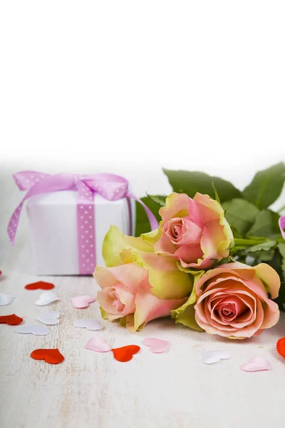 Розовые розы, подарок и сердца на деревянном фоне . — стоковое фото