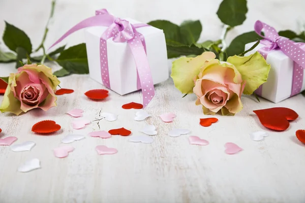 Růžové růže, dar a srdce na dřevěné pozadí. — Stock fotografie