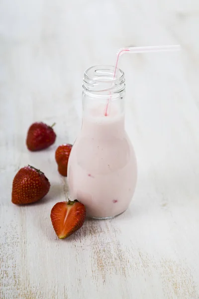 Smoothies e morango maduro em uma mesa de madeira . — Fotografia de Stock