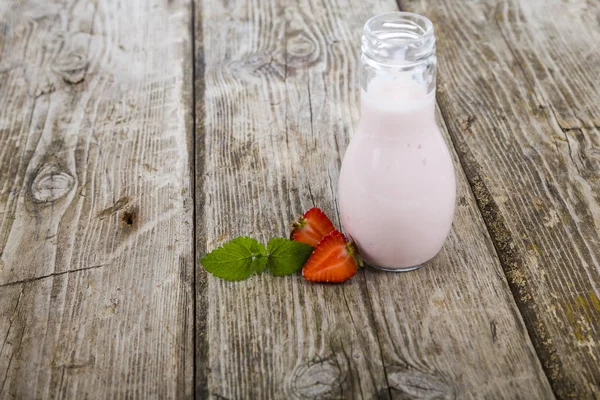 Smoothies e morango maduro em uma mesa de madeira . — Fotografia de Stock