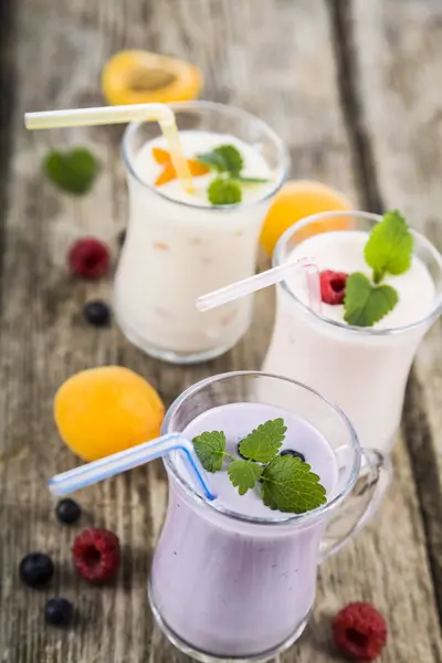 Batidos o yogurt con bayas frescas sobre una mesa de madera . — Foto de Stock