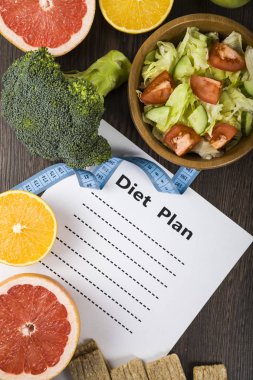 Gıda ve koyu ahşap bir masa üzerinde bir diyet planı ile kağıt.