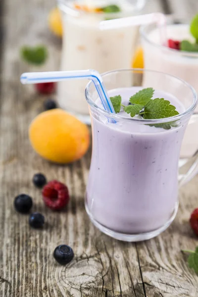 Smoothies ou iogurte com bagas frescas em uma mesa de madeira . — Fotografia de Stock