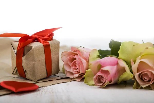 Růžové růže, dar a srdce na dřevěné pozadí. — Stock fotografie