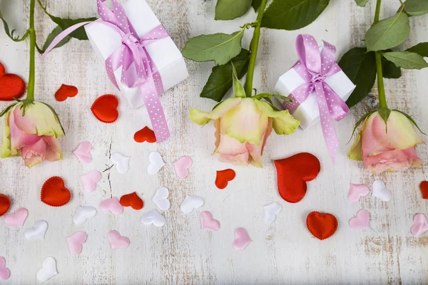 Rosas rosadas, regalos y corazones sobre un fondo de madera . — Foto de Stock