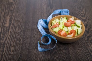 Ahşap kase ve bir tablo yakın çekim üzerinde ölçüm bandı salata. 
