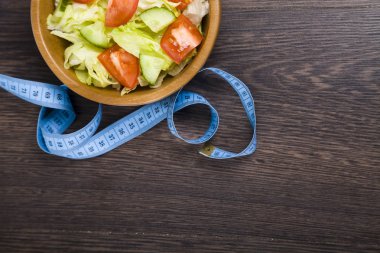 Ahşap kase ve bir tablo yakın çekim üzerinde ölçüm bandı salata. 