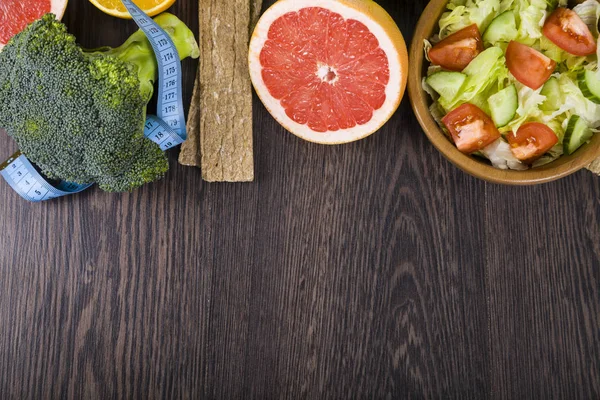 Nourriture pour alimentation et ruban à mesurer sur une table en bois sombre . — Photo