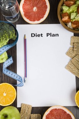 Gıda ve koyu ahşap bir masa üzerinde bir diyet planı ile kağıt.
