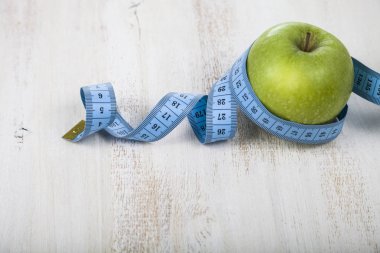 Yeşil elma ve ahşap bir masa üzerinde ölçüm bandı.  