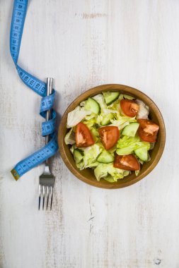 Ahşap kase, çatal ve bir tablo kapat-u üzerinde ölçüm bandı salata