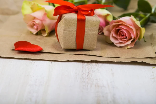 Rosas rosadas, regalos y corazones sobre un fondo de madera . — Foto de Stock