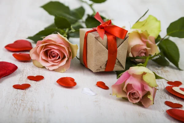 Róż, prezent i serca na tle drewnianych. — Zdjęcie stockowe
