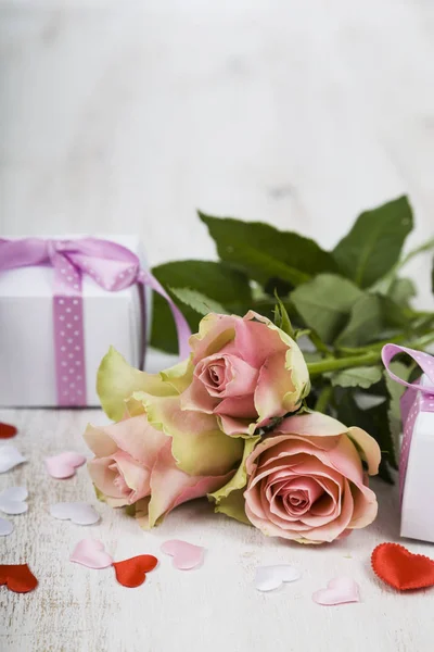 Rosa Rosen, Geschenk und Herzen auf einem hölzernen Hintergrund. — Stockfoto