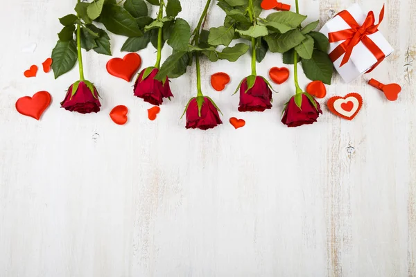 Rosas vermelhas e corações em um fundo de madeira . — Fotografia de Stock