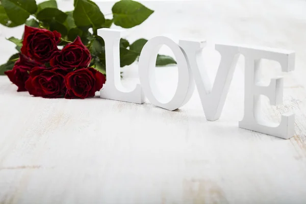 Frame van rode rozen en woord "Love" op een houten achtergrond. — Stockfoto