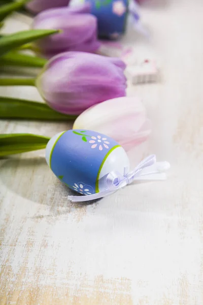 Bukett lila tulpaner och påskägg på ett ljust träbord. — Stockfoto