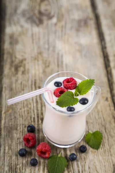 Smoothies ou iogurte com bagas frescas em uma mesa de madeira . — Fotografia de Stock