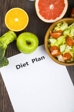 Gıda ve koyu ahşap bir masa üzerinde bir diyet planı ile kağıt.