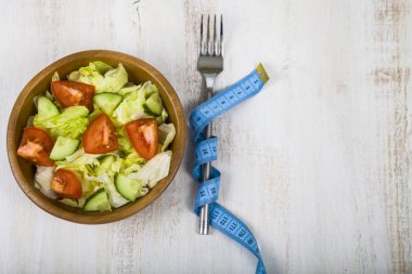 Ahşap kase, çatal ve bir tablo kapat-u üzerinde ölçüm bandı salata