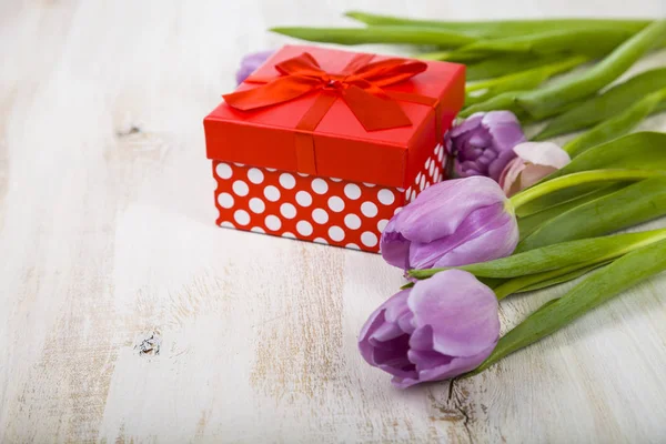 Bouquet di tulipani e un regalo su uno sfondo di legno . — Foto Stock