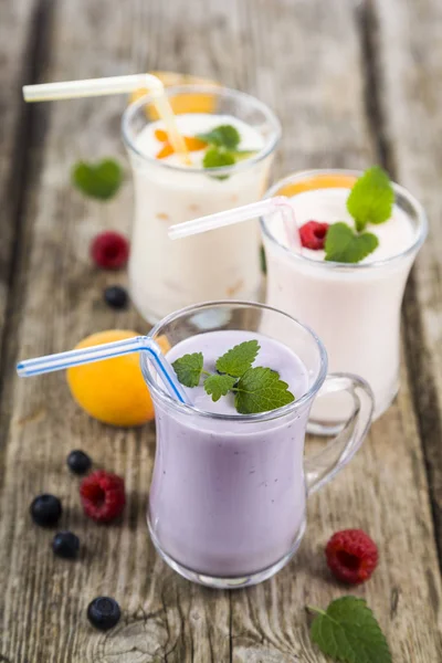 Tres vasos con batidos o yogur con bayas frescas en un —  Fotos de Stock