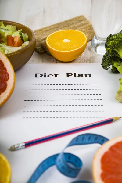 Food and sheet of paper with a diet plan on a dark wooden table. — Stock Photo, Image