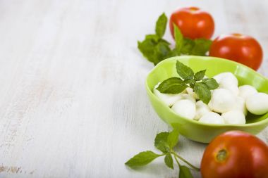 Mozzarella ahşap bir masa üzerinde yeşil bir tabak içinde. Mozzarella topları 