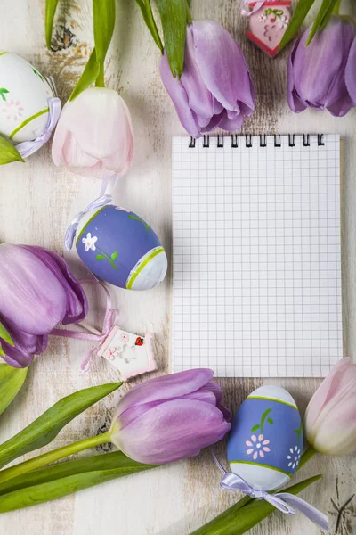 Bouquet purple tulips, paper and Easter eggs on a light wooden t — Stock Photo, Image