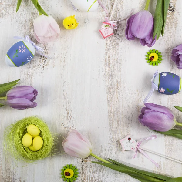 Bouquet purple tulips and Easter eggs on a light wooden table. — Stock Photo, Image
