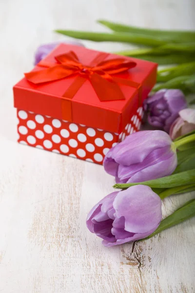 Bouquet de tulipes et un cadeau sur fond de bois . — Photo
