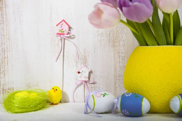 Bouquet purple tulips and Easter eggs on a light wooden table. — Stock Photo, Image