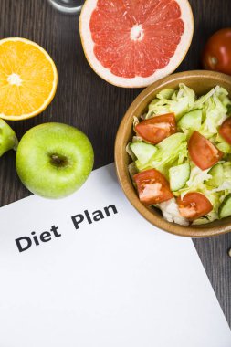 Gıda ve koyu ahşap bir masa üzerinde bir diyet planı ile kağıt.