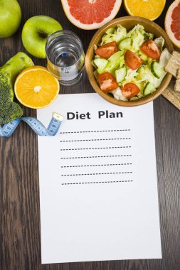 Gıda ve koyu ahşap bir masa üzerinde bir diyet planı ile kağıt.