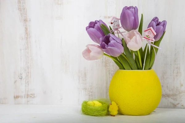 Ramo de tulipanes morados y huevos de Pascua en una mesa de madera clara . — Foto de Stock