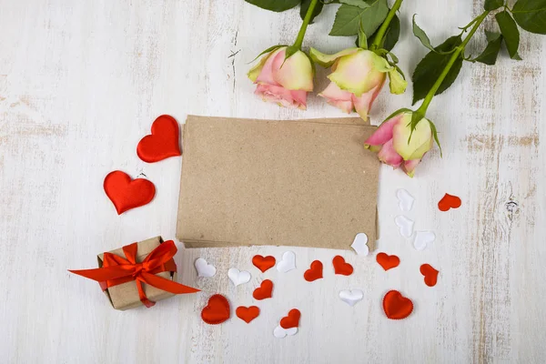 Rosas rosadas, regalos y corazones sobre un fondo de madera . — Foto de Stock