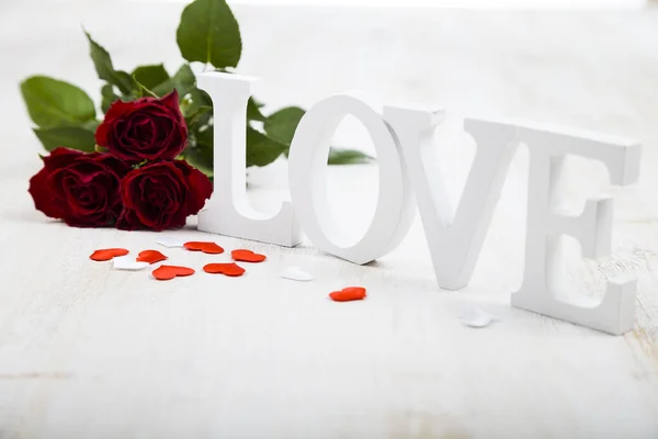 Rode rozen, harten en woord "Love" op een houten achtergrond. — Stockfoto