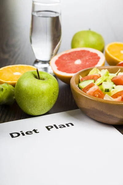Food and sheet of paper with a diet plan on a dark wooden table. — Stock Photo, Image