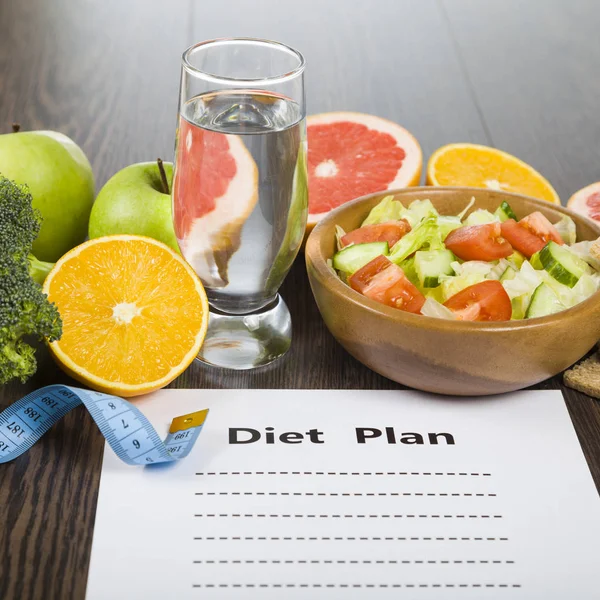 Food and sheet of paper with a diet plan on a dark wooden table. — Stock Photo, Image