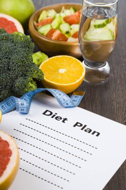 Gıda ve koyu ahşap bir masa üzerinde bir diyet planı ile kağıt.