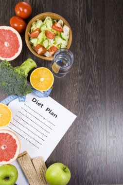 Gıda ve koyu ahşap bir masa üzerinde bir diyet planı ile kağıt.