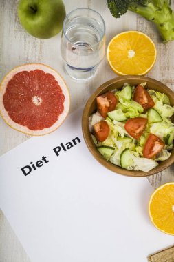 Gıda ve koyu ahşap bir masa üzerinde bir diyet planı ile kağıt.