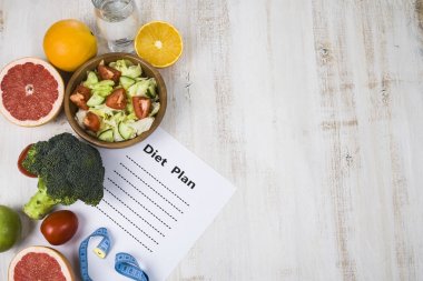 Gıda ve koyu ahşap bir masa üzerinde bir diyet planı ile kağıt.