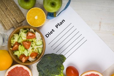 Gıda ve koyu ahşap bir masa üzerinde bir diyet planı ile kağıt.