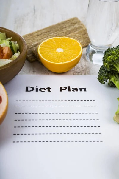 Food and sheet of paper with a diet plan on a dark wooden table. — Stock Photo, Image