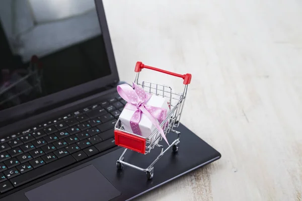 Carrito de compras con caja de regalo en portátil. Concepto de compras onlin — Foto de Stock