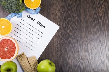 Gıda ve koyu ahşap bir masa üzerinde bir diyet planı ile kağıt.