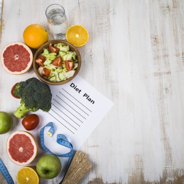 Gıda ve koyu ahşap bir masa üzerinde bir diyet planı ile kağıt.