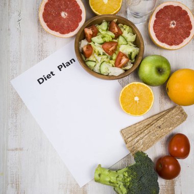 Gıda ve koyu ahşap bir masa üzerinde bir diyet planı ile kağıt.