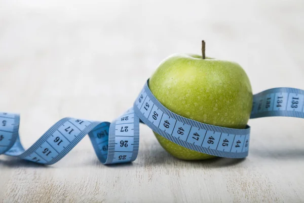 Manzana verde y cinta métrica en una mesa de madera . —  Fotos de Stock